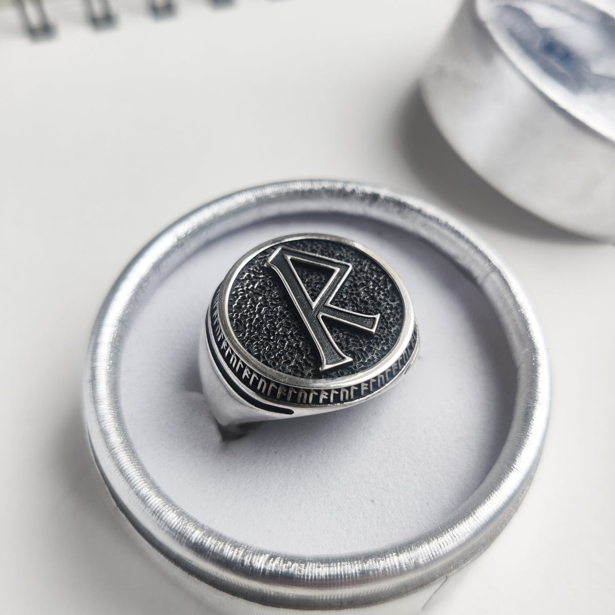 Raido rune men’s signet ring displayed in a silver dish, highlighting its substantial profile — INDIGO Jewelry.