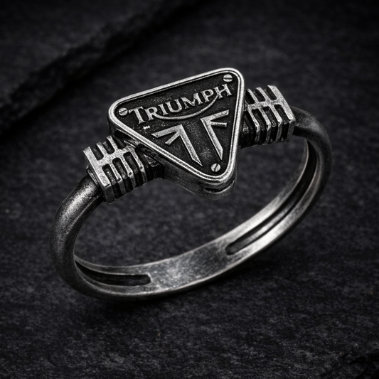A silver ring with a metal emblem featuring the word "TRIUMPH" on it.