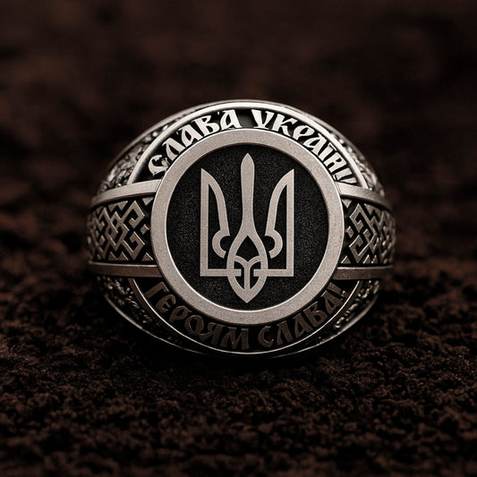 A silver ring with a black and white emblem, surrounded by intricate patterns and designs.