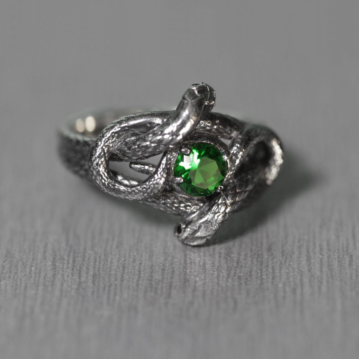 Anillo de plata de ley para mujer con nudo de serpiente y piedra preciosa verde.