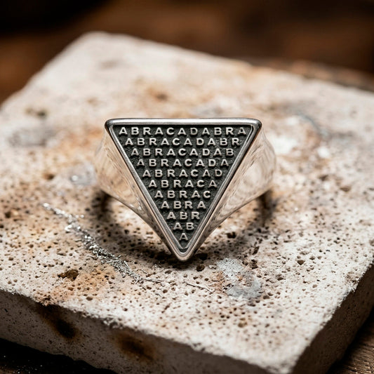 Handcrafted Abracadabra ring with black onyx-style background and polished silver letters resting on a ceramic soldering block in Indigo Atelier.