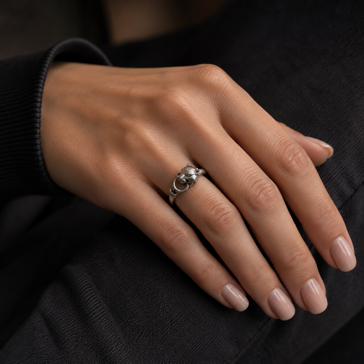 Young woman wearing sterling silver panther head ring with black gemstones on ring finger