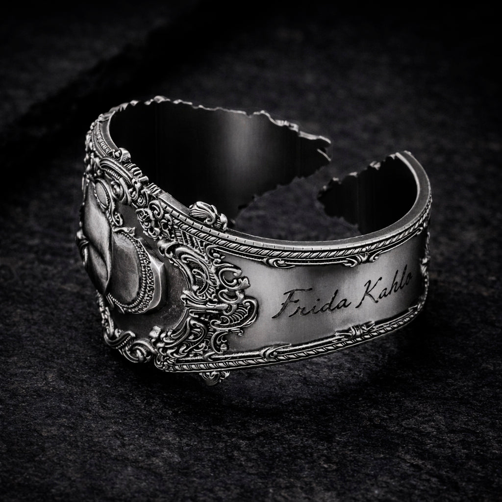 Open oxidized silver thumb ring featuring a detailed portrait of Frida Kahlo. Artistic spoon ring inspired by vintage silverware jewelry, designed as an open ring that wraps tightly around the thumb. Statement thumb ring with sculptural relief and darkened recessed details, handcrafted art jewelry. Frida Kahlo open ring made of blackened silver, bold spoon ring for the thumb, unique wearable art.