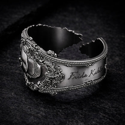 Open oxidized silver thumb ring featuring a detailed portrait of Frida Kahlo. Artistic spoon ring inspired by vintage silverware jewelry, designed as an open ring that wraps tightly around the thumb. Statement thumb ring with sculptural relief and darkened recessed details, handcrafted art jewelry. Frida Kahlo open ring made of blackened silver, bold spoon ring for the thumb, unique wearable art.