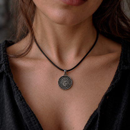 Woman wearing the silver Hel pendant on a black cord, with the divided face visible. INDIGO Jewelry.