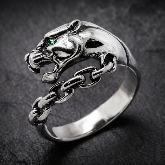 A silver ring with a silver Panthera head design and a chain-link chain attached to it. Green zircon in the eye. Indigo Jewelry.