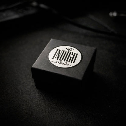 A black box with a white circular label that says "INDIGO Style" on it, placed on a dark surface.