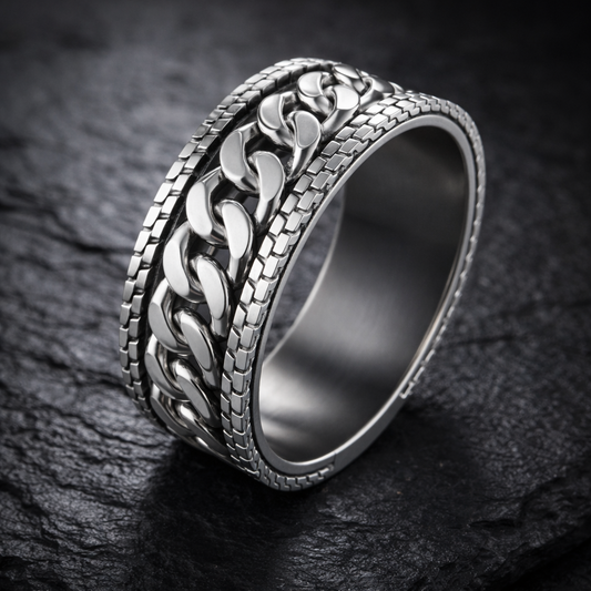 A silver ring with a unique chain design, resting on a dark surface.
