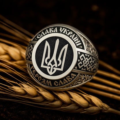 A close-up image of a ring with a circular design featuring a stylized emblem, surrounded by intricate patterns and text.