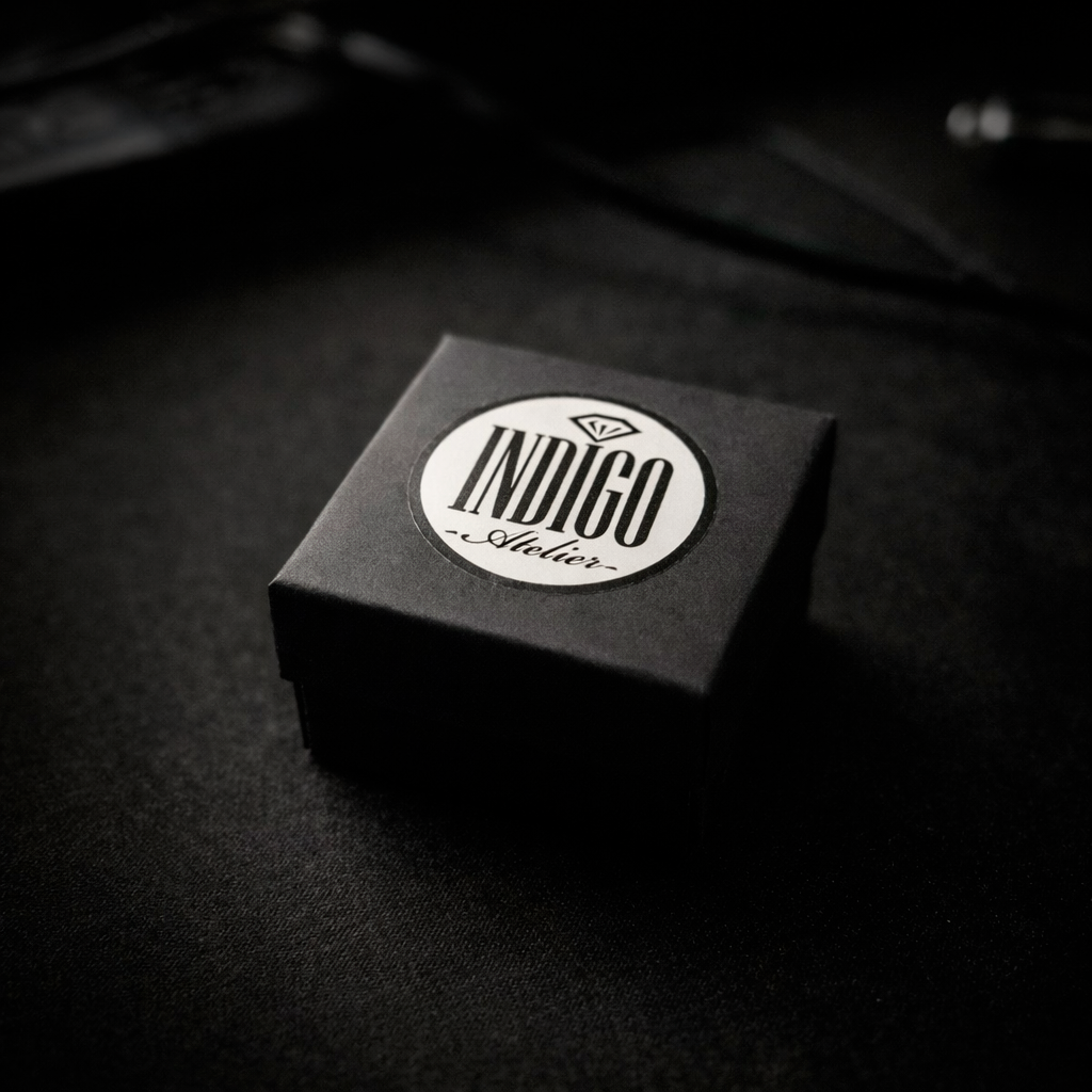 A black and white image of a small, square-shaped box with a white circular label on it, placed on a dark surface.