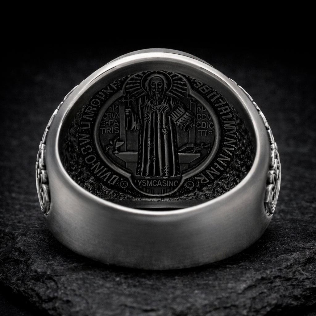 a silver ring with a detailed engraved design on the back, depicting a religious figure.