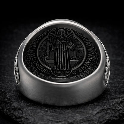 a silver ring with a detailed engraved design on the back, depicting a religious figure.