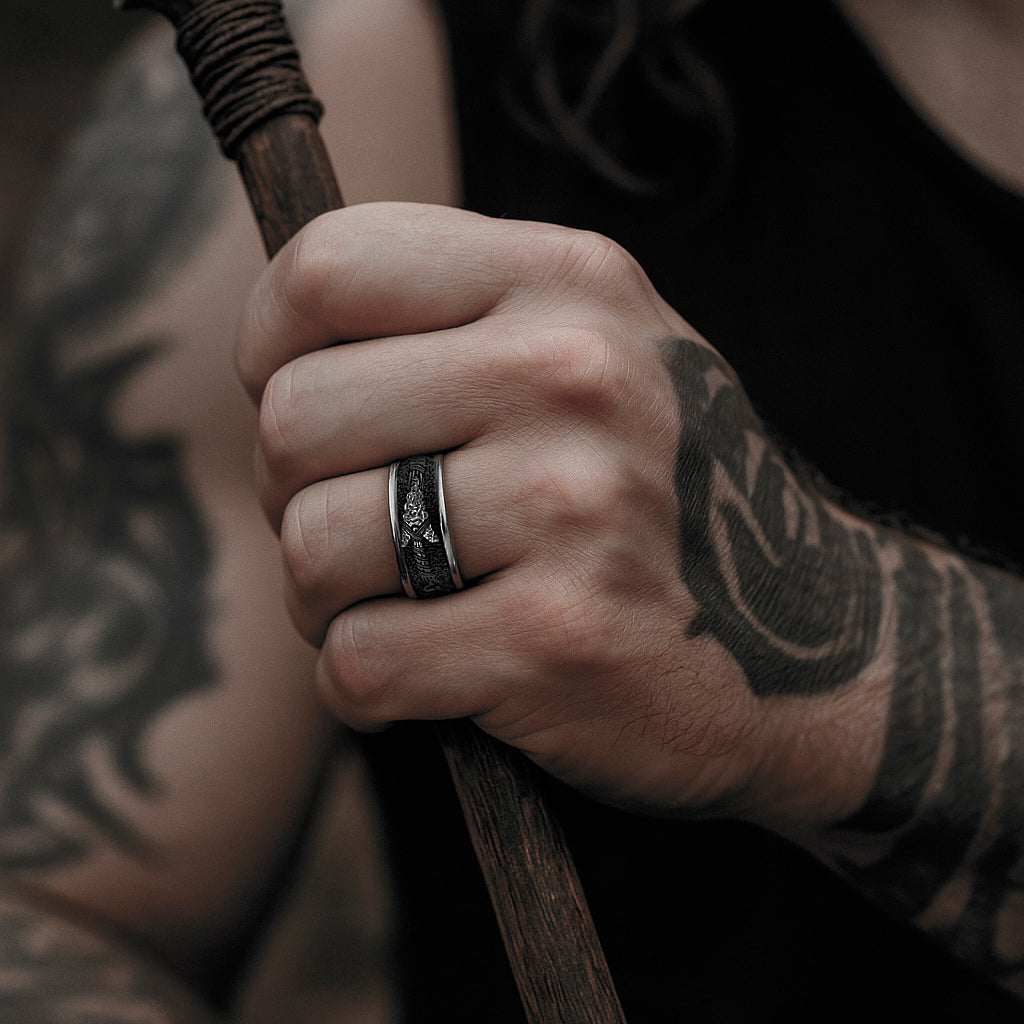 A close-up of a person's hand holding a wooden stick, with tattoos visible on their arm.