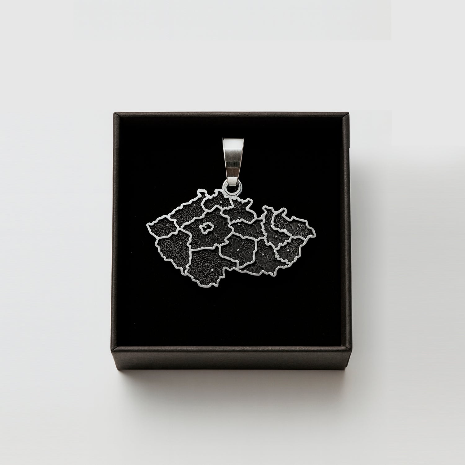 A pendant in the shape of a map of the Czech Republic, displayed in a black box.