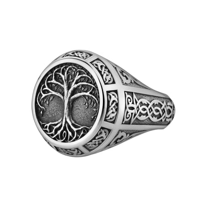 A silver ring with an intricate tree design on the front.