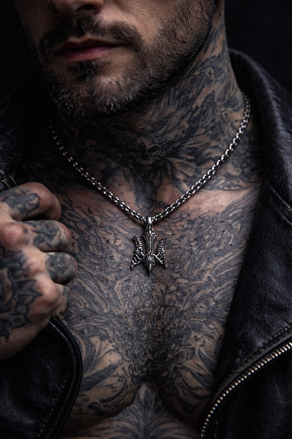 A close-up of a tattooed man wearing a silver necklace and a leather jacket. gothic-trident-pendant-ukrainian-tryzub-sterling-silver-dark-alternative-jewelry-mens-gothic-pendant-handmade-silver-pendant-dark-style-biker-goth-fantasy-metal-jewelry-unisex-statement-pendant-artisan-silver-jewelry-gothic-symbol-trident-necklace-without-chain-indie-brand-indigo-jewelry-handcrafted-925-silver-dark-aesthetic