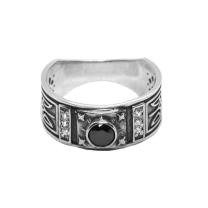 A silver ring with a black gemstone in the center, surrounded by intricate designs and patterns.