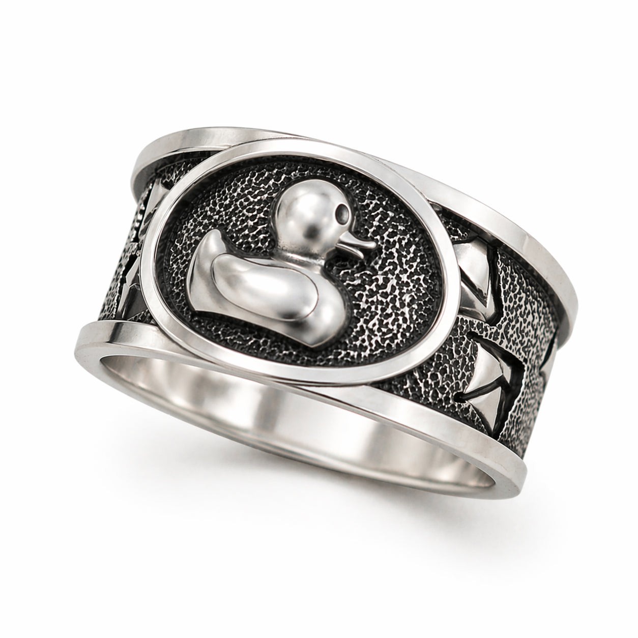 Sterling silver duck signet ring with oxidized textured background and polished raised duck symbol. Wide band design with detailed engraving and strong contrast. Minimalist yet expressive jewelry piece photographed on clean background and lifestyle scenes, including close-up macro views and on-hand shots. Designed as a unique statement ring for men and women, combining craftsmanship, symbolism, and modern style.