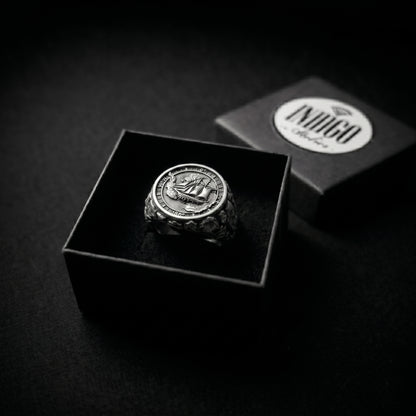 Antarctica explorer signet ring in solid sterling silver 925 featuring a detailed sailing ship over a map of Antarctica, surrounded by directional markings. The ring has a deep oxidized finish with strong contrast, highlighting fine handcrafted textures and relief details. Shot on a dark stone background to emphasize its bold, masculine design, adventure theme, and expedition spirit. Unique nautical jewelry piece inspired by travel, ocean journeys, and exploration beyond the known world.