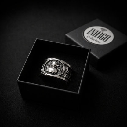 A silver ring with a duck design is displayed in a black jewelry box, with the box's lid visible in the background.