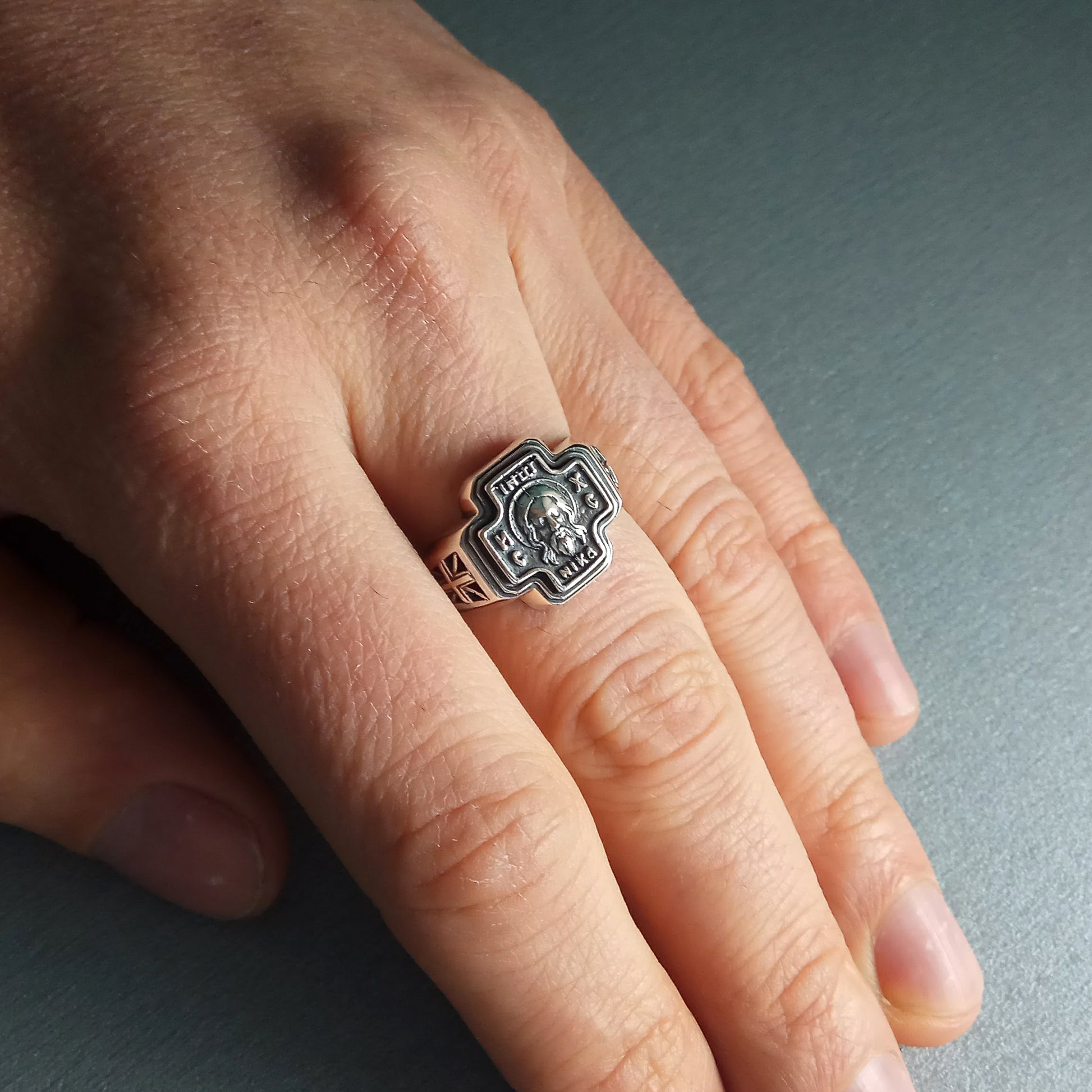 A close-up of a person's hand wearing a silver ring with a skull design.