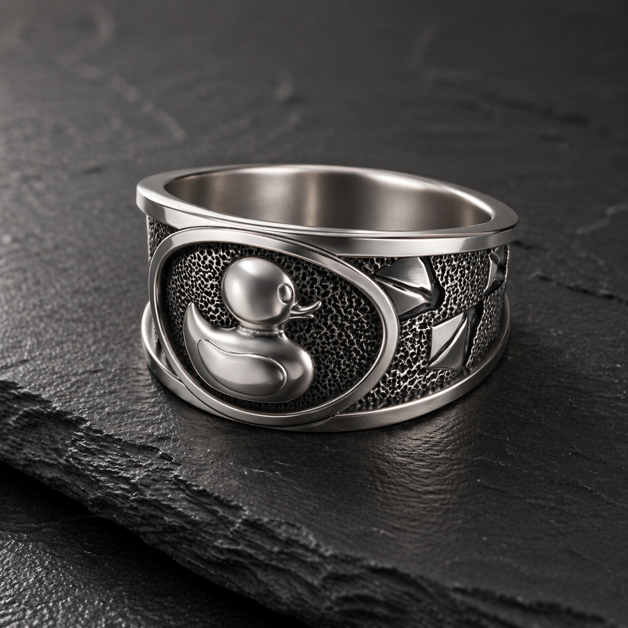 A silver ring with a detailed design featuring a duck and a fish.