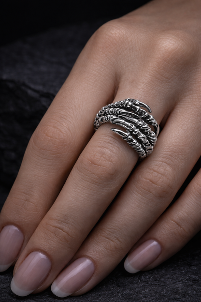 A close-up image of a person's hand wearing a silver ring with intricate designs.