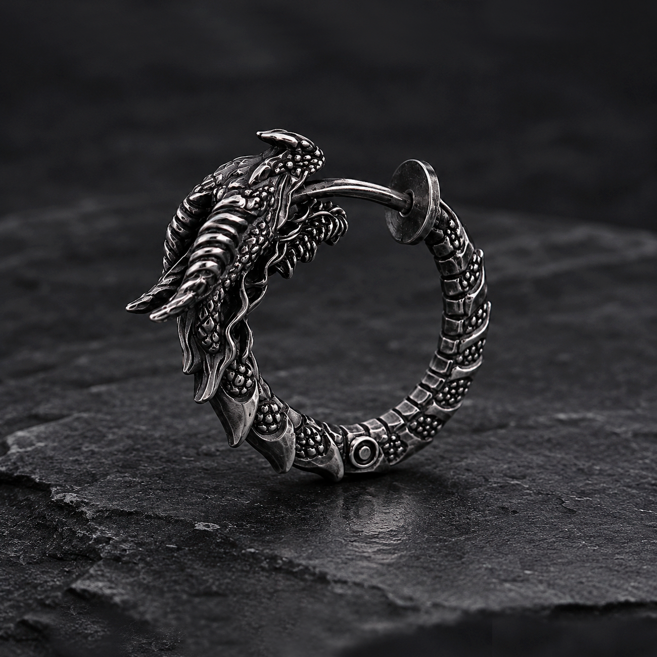 Handcrafted dragon hoop earring in oxidized sterling silver 925 by INDIGO Jewelry. Detailed gothic silver earring featuring a sculpted dragon head, textured scales, and a segmented hoop with blackened oxidized finish for a dark vintage appearance. Realistic fantasy-inspired jewelry with medieval and mythical aesthetics, designed as a bold statement piece for dragon lovers, gothic fashion, alternative style, and symbolic silver jewelry collections.