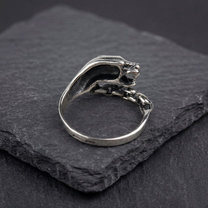 A silver ring with a silver Panthera head design and a chain-link chain attached to it. Green zircon in the eye. Indigo Jewelry. Backside.