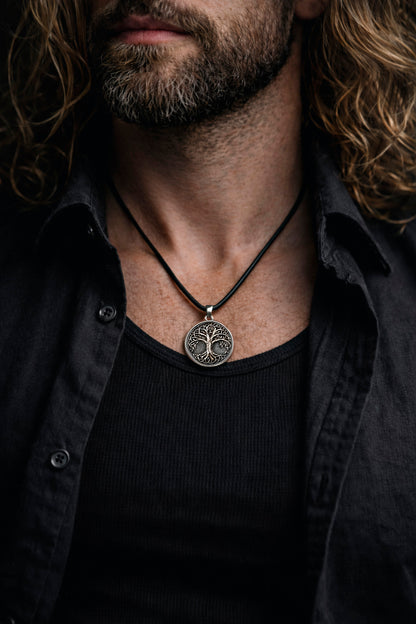 Oxidized silver Tree of Life pendant in 925 sterling silver, inspired by Yggdrasil Norse mythology, round 25mm symbolic Viking necklace, handcrafted Scandinavian jewelry for men, detailed textured background, minimalist mythological silver charm