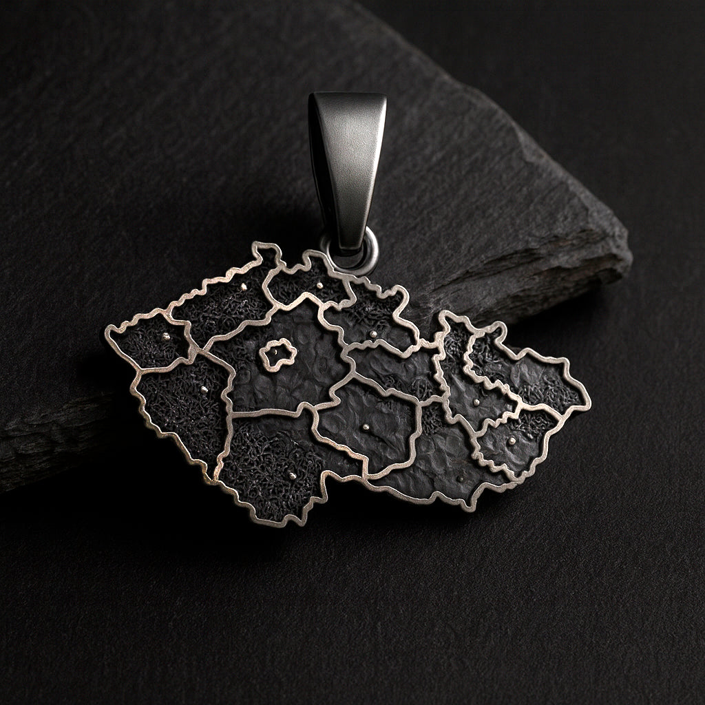 A pendant in the shape of a map of the Czech Republic, made of metal and featuring a dark, textured design.