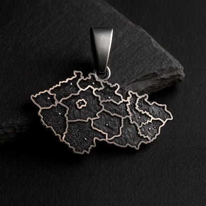 A pendant in the shape of a map of the Czech Republic, made of metal and featuring a dark, textured design.