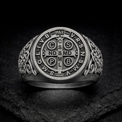 A silver ring with an intricate design featuring a cross and various religious symbols.