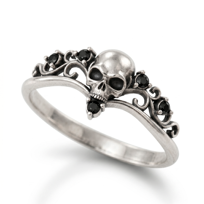 Dainty gothic engagement ring made of blackened 925 sterling silver, featuring a detailed skull design with black gemstones. Elegant womens silver goth ring in a skull ring style, isolated on a clean white catalog background with a soft gradient shadow.
