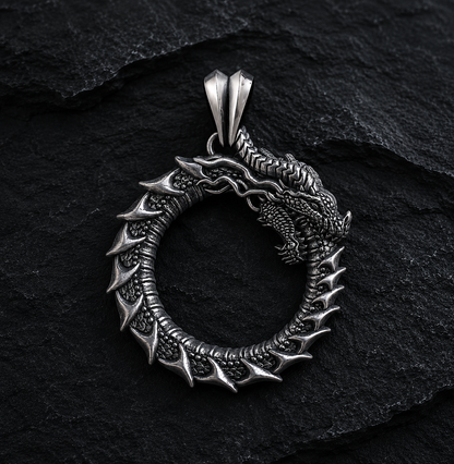 Ouroboros dragon pendant in oxidized sterling silver 925 by INDIGO Jewelry on a dark textured background. Handcrafted symbolic dragon necklace inspired by mythology, featuring detailed scales and an ancient eternity symbol.