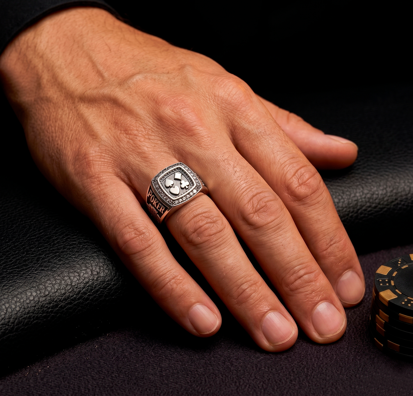 Close-up of the premium silver poker signet ring by Indigo Jewelry on a man's hand at a casino table.